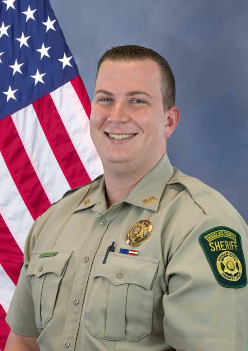 Portrait of a Douglas County Sheriff deputy in uniform with American flag in the background.