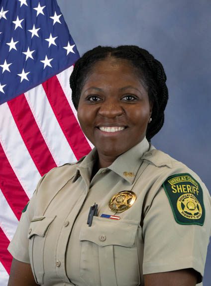 Portrait of a Douglas County Sheriff deputy in uniform standing in front of an American flag.