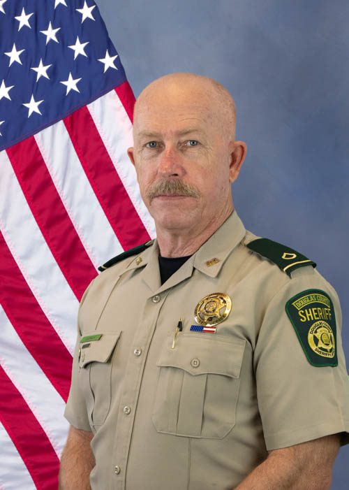 Portrait of a Douglas County sheriff officer in uniform standing in front of a U.S. flag.