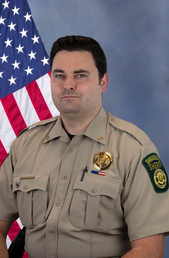 Portrait of a Douglas County sheriff in uniform with American flag in the background.